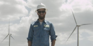 Wind Turbine Technician James Van Dyken stands in front of wind farm.