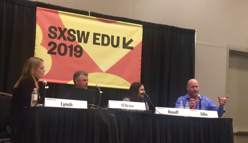 Panelists sit at table on stage for panel discussion at SXSW EDU.