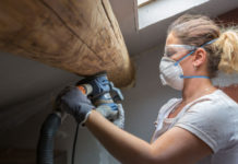 Woman sanding wood beam in home