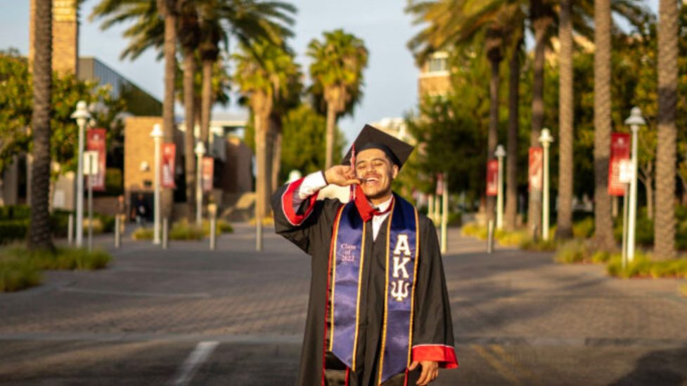 A student with experience in foster care wears his college graduation robe