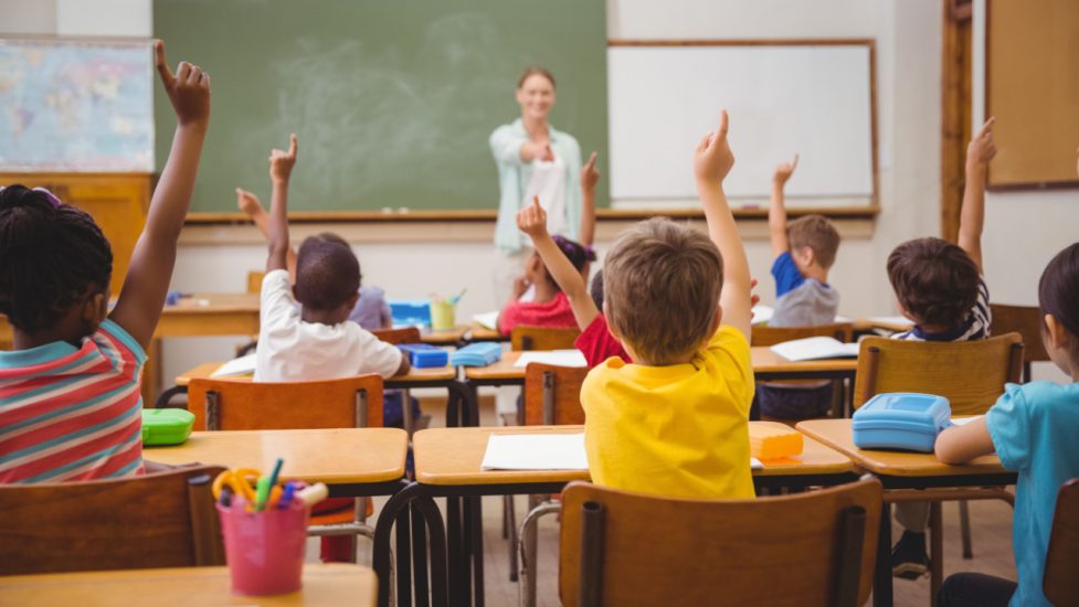 teacher in classroom with raised hands